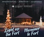 Historical log cabin at night with strings of lights and lit up trees.