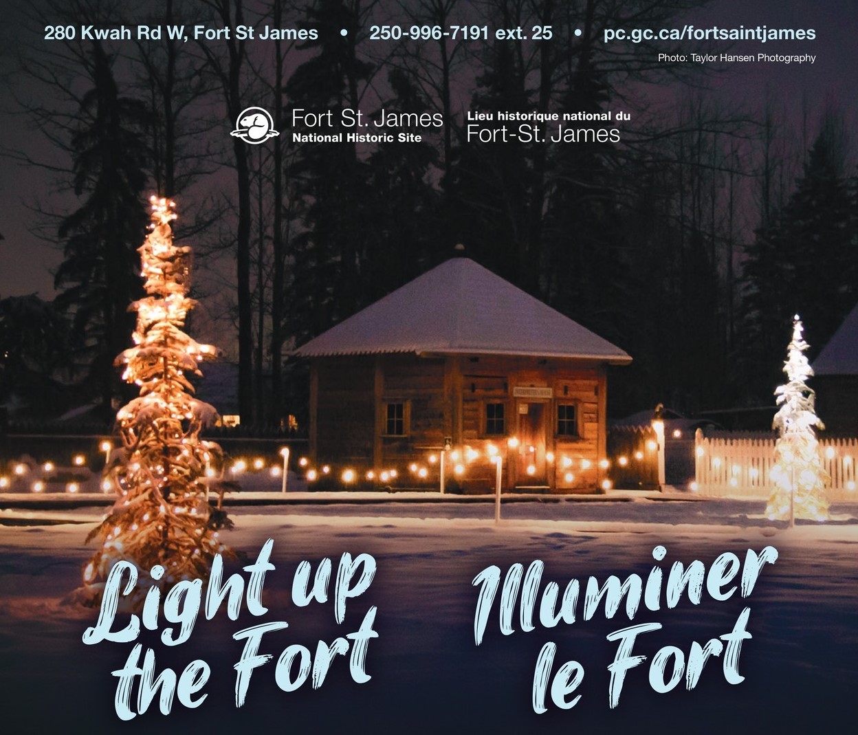 Historical log cabin at night with strings of lights and lit up trees.